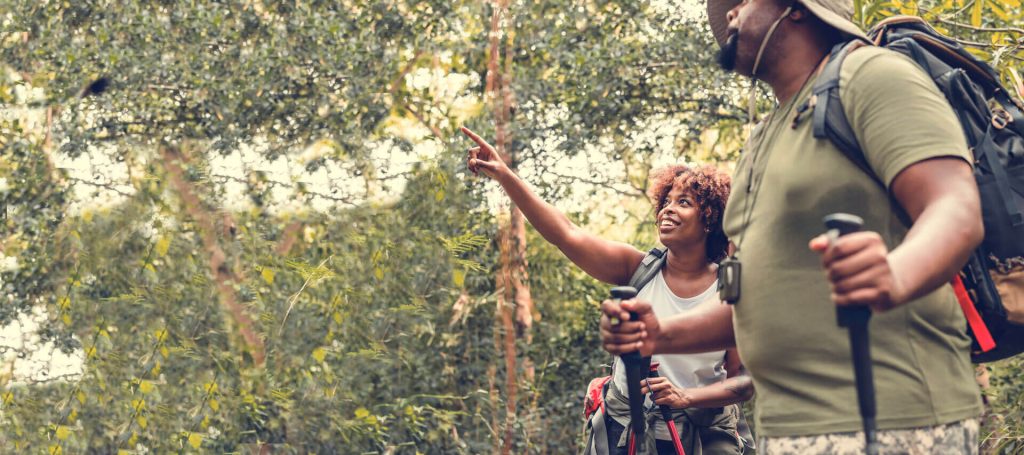 Photo of a male and female hiker. The female hiker is pointing at something in the distance.